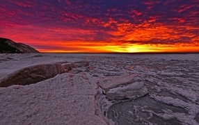 Красный закат солнца покрывает заледеневшее озеро 
