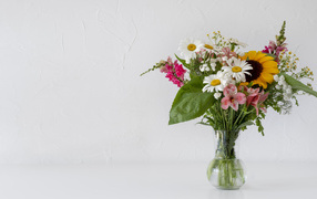 Beautiful summer bouquet in a glass vase on a gray background