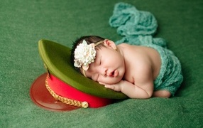 A small child sleeps on a military cap