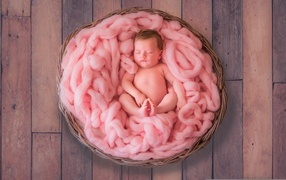 Ребенок спит в корзине с розовым покрывалом