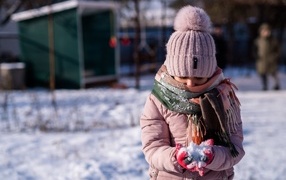 Девочка держит снег в руках зимой