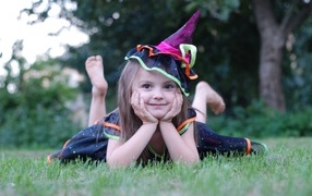 Девочка в костюме лежит на зеленой траве