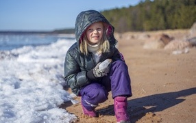 Девочка сидит у замерзшего озера 