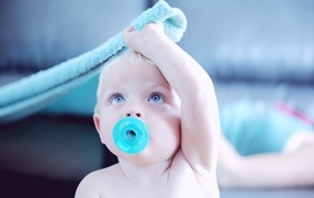 Little baby with a blue pacifier in his mouth