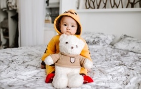 Маленький ребенок с игрушкой на кровати 