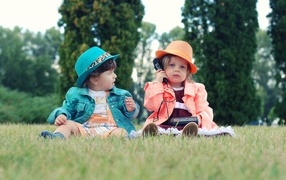 Little girl and boy are sitting on the grass