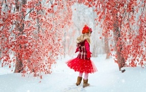 Маленькая девочка в красном платье в зимнем лесу