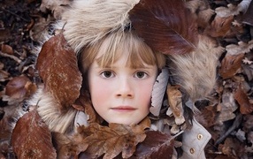 Маленькая девочка лежит в опавшей листве