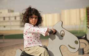 Маленькая девочка на деревянной лошади