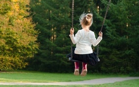 Little girl rides on a swing