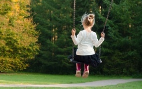 Маленькая девочка катается на качели