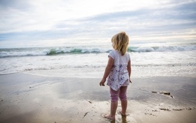 Маленькая девочка стоит на берегу моря