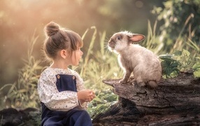 Маленькая девочка с кроликом в саду