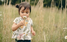 Маленькая девочка с ромашкой на поле