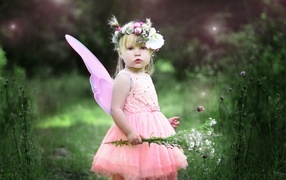 Little girl with flowers in a pink fairy dress