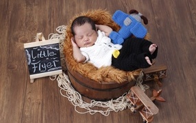 Маленький новорожденный малыш спит в бочке 