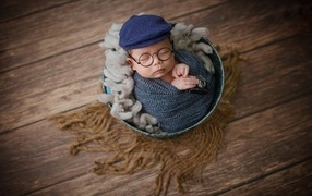 Маленький новорожденный ребенок в очках и кепке 