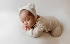 Little sleeping child in a knitted suit on a gray background