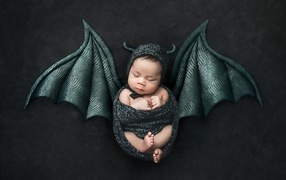 Маленький спящий ребенок с крыльями на Хэллоуин