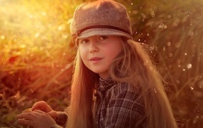Длинноволосая девочка в кепке в лучах солнца