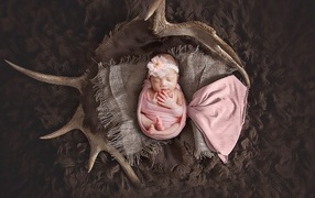 Новорожденная девочка на покрывале с рогами