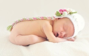 Новорожденная девочка спит в шапке