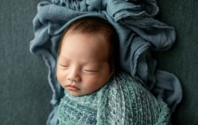 Newborn baby wrapped in a gray blanket