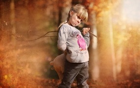 Обиженная девочка с игрушкой и палкой в лесу 