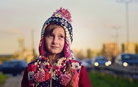 Грустная девочка в теплой шапке на улице