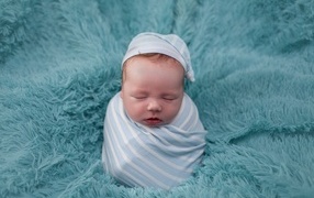 Спящий новорожденный малыш на голубом покрывале 