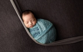 Маленький спящий ребенок завернут в покрывало