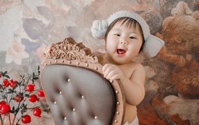 Улыбающийся ребенок азиат стоит у кресла