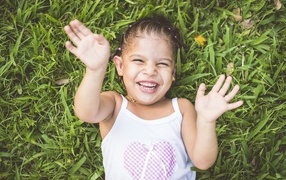 Улыбающаяся девочка лежит на траве