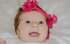 Улыбающаяся маленькая девочка с цветком на голове