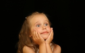 Удивленная маленькая девочка на черном фоне