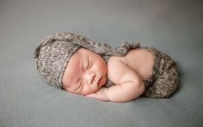 Ребенок спит в костюме на сером покрывале