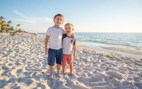 Два маленьких мальчика стоят на песке у моря
