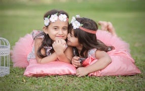 Две маленькие девочки лежат на подушках на траве