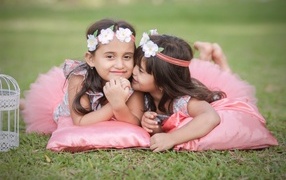 Две маленькие девочки лежат на подушках на траве