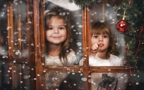 Two little girls sitting by the window at Christmas