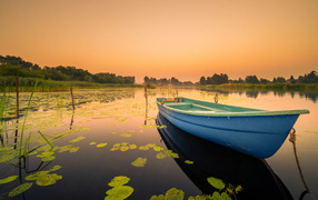 Голубая лодка в озере на закате солнца