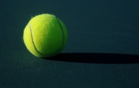 Маленький теннисный мяч на сером поле