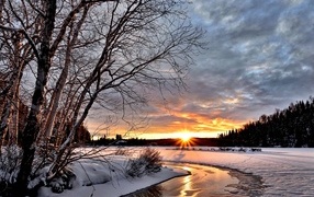 Bright winter sun at dawn over an icy river