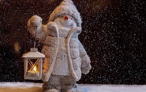 Toy snowman with a flashlight in the snow