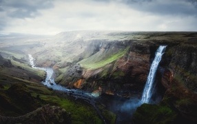 Waterfall flows from a cliff into a canyon, Iceland
