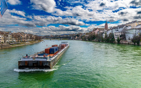 A cargo river boat floats down the river near houses, Switzerland
