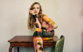 Актриса Аманда Сайфред в платье сидит на столе