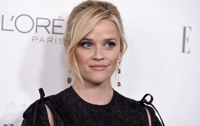 Actress Reese Witherspoon in a black dress against a wall