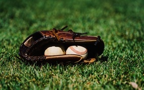 Baseball glove and balls on green grass