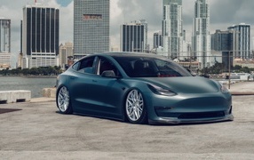 Electric car Tesla Model 3 on the background of skyscrapers